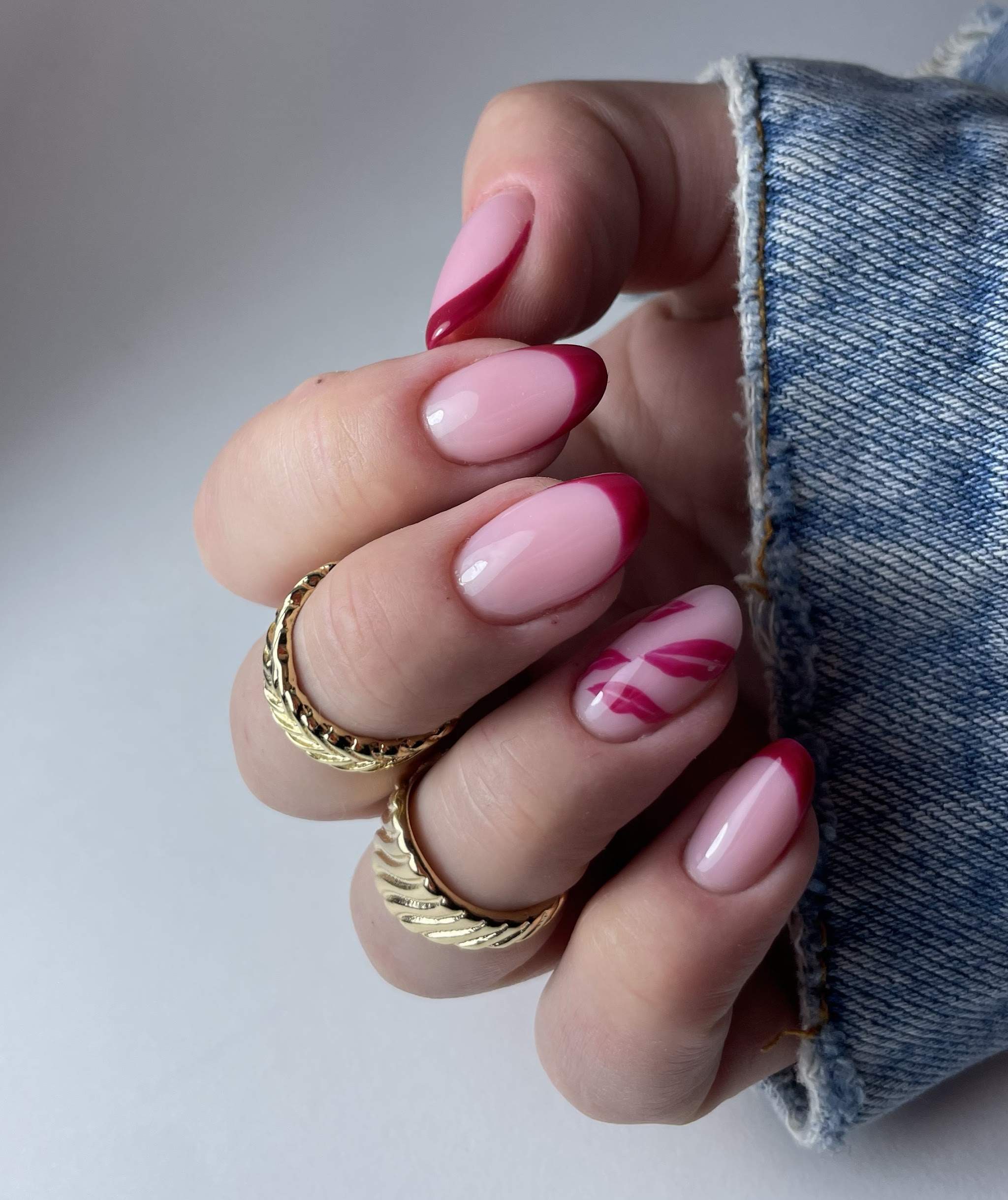 Roze amandelnagels met rode French tips en een rood abstract accent