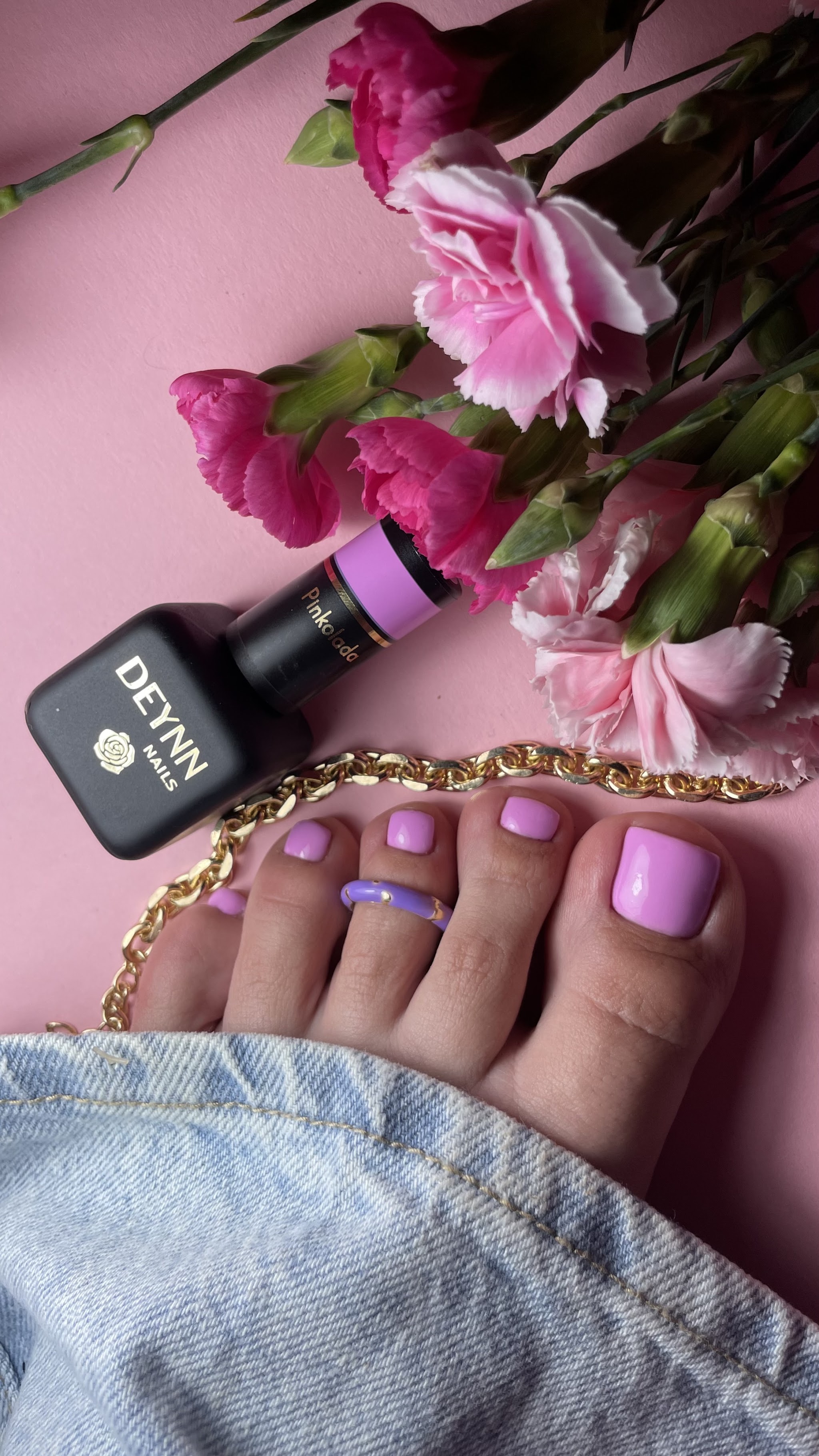 Lila gellak pedicure met een flesje nagellak en roze bloemen